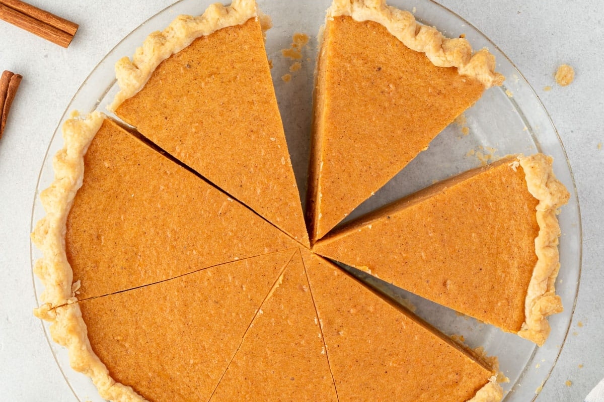 A pumpkin pie with a slice taken out of it.