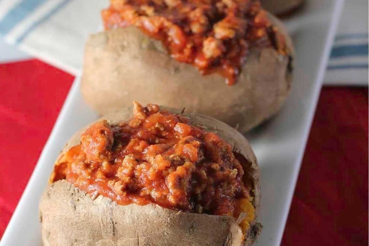 Stuffed sweet potatoes with meat sauce on a white plate.