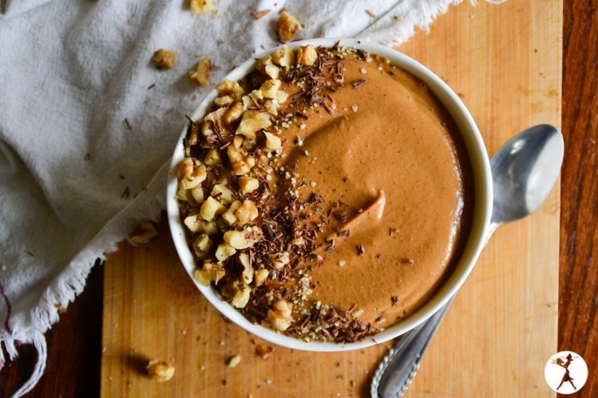A chocolate and sweet potato smoothie bowl with nuts on a cutting board.