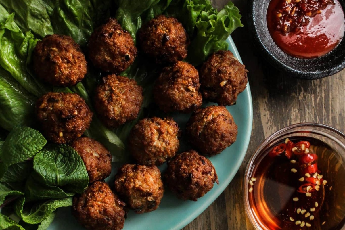 Vietnamese meatballs on a plate with dipping sauce.