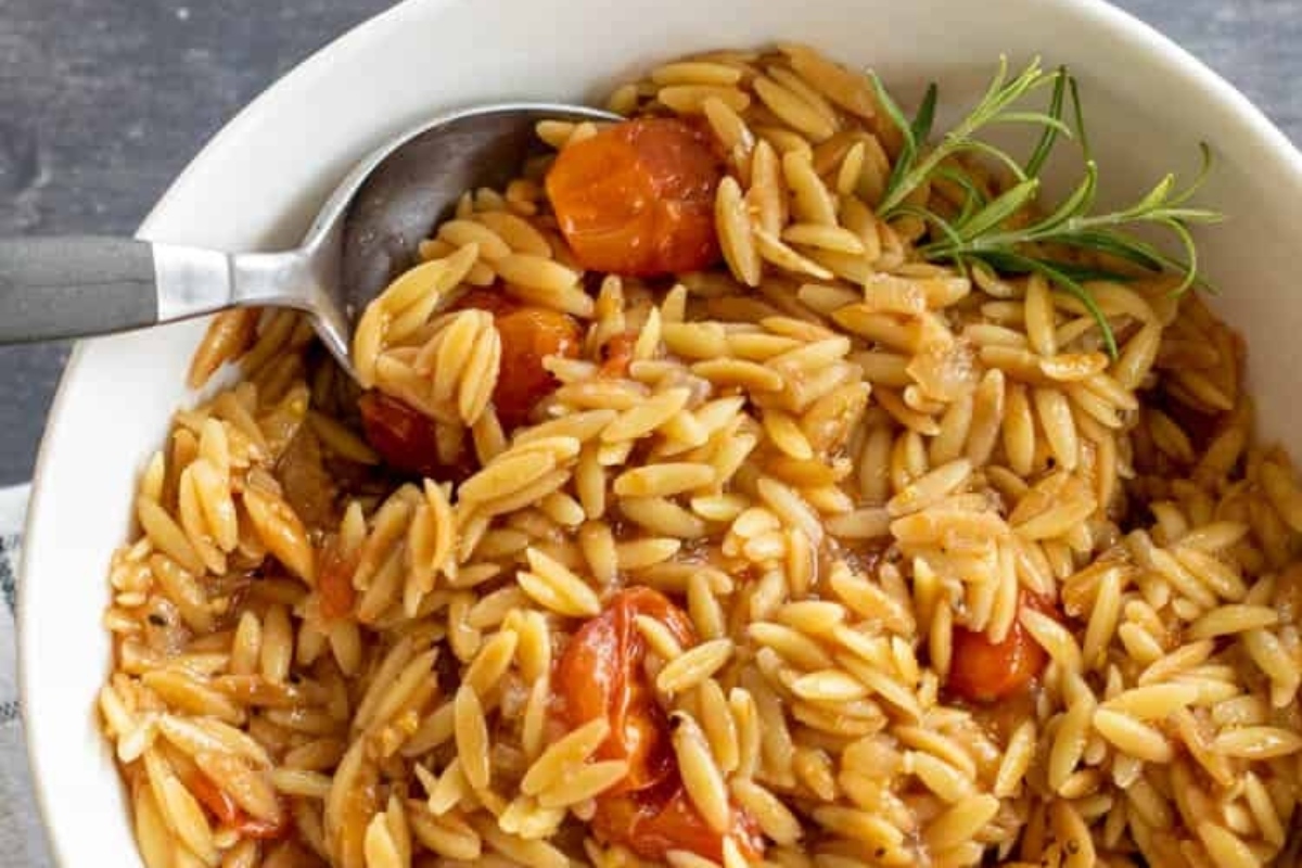 A bowl of pasta with carrots and rosemary.