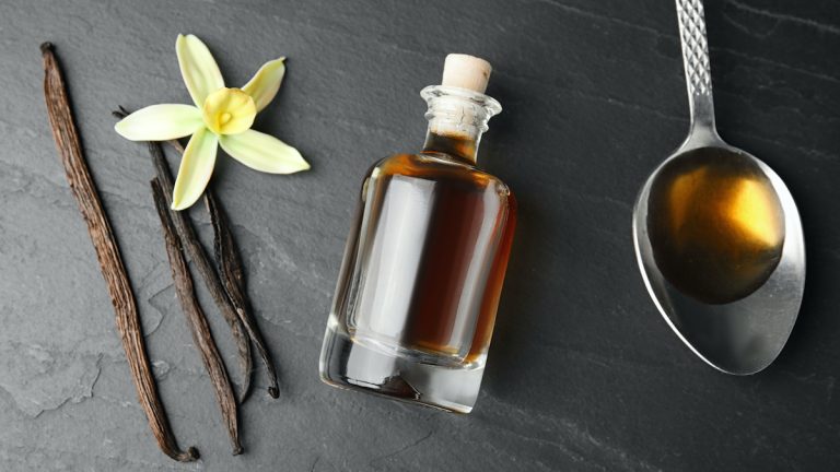 Flat lay composition with vanilla extract on black table.