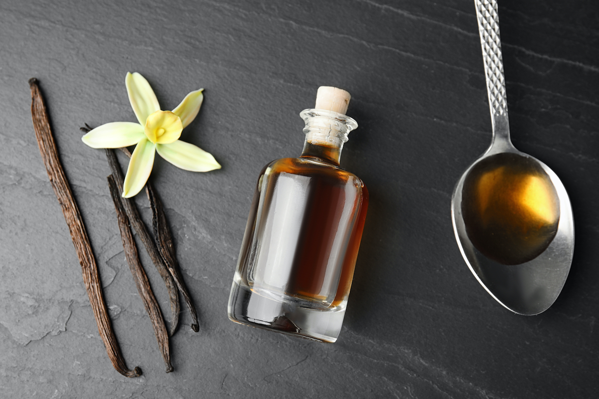 Flat lay composition with vanilla extract on black table.