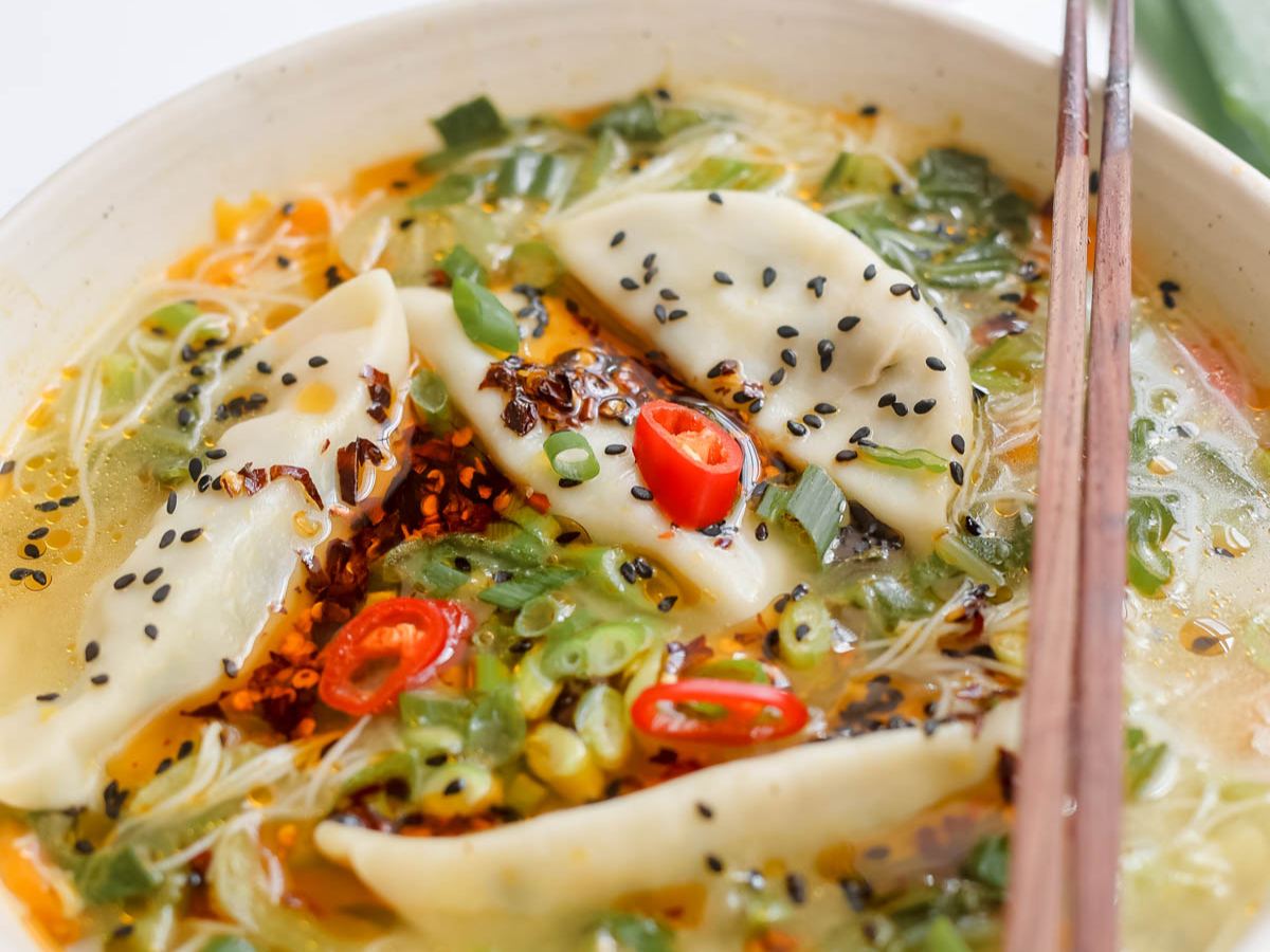 Bowl of soup with dumplings and chopsticks.