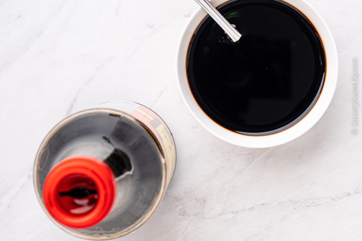 A bowl of soy sauce next to a spoon.