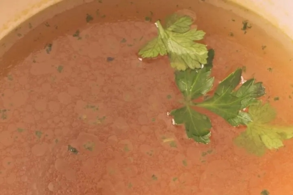 A bowl of tomato soup with parsley on top.