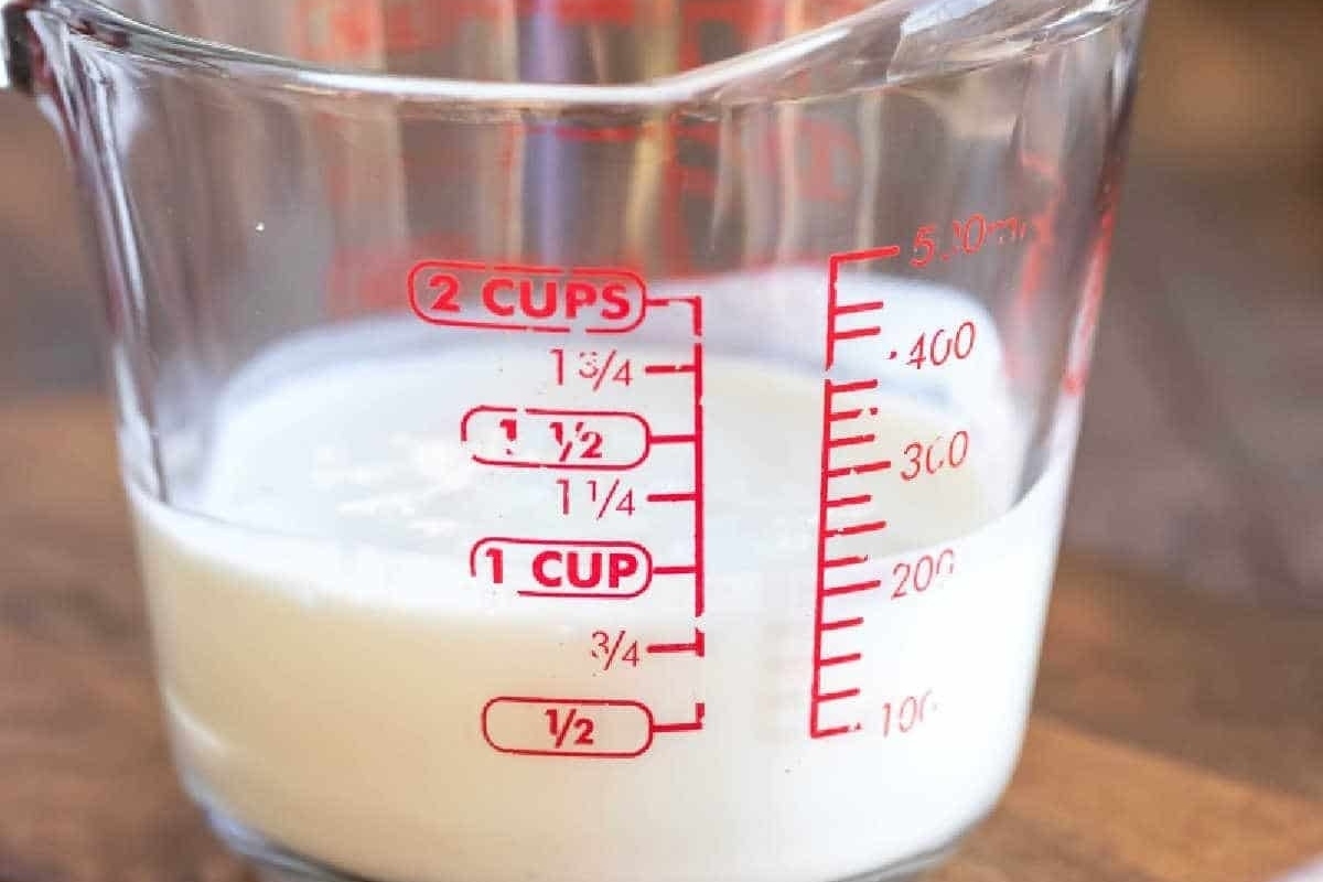 A measuring cup with milk in it.