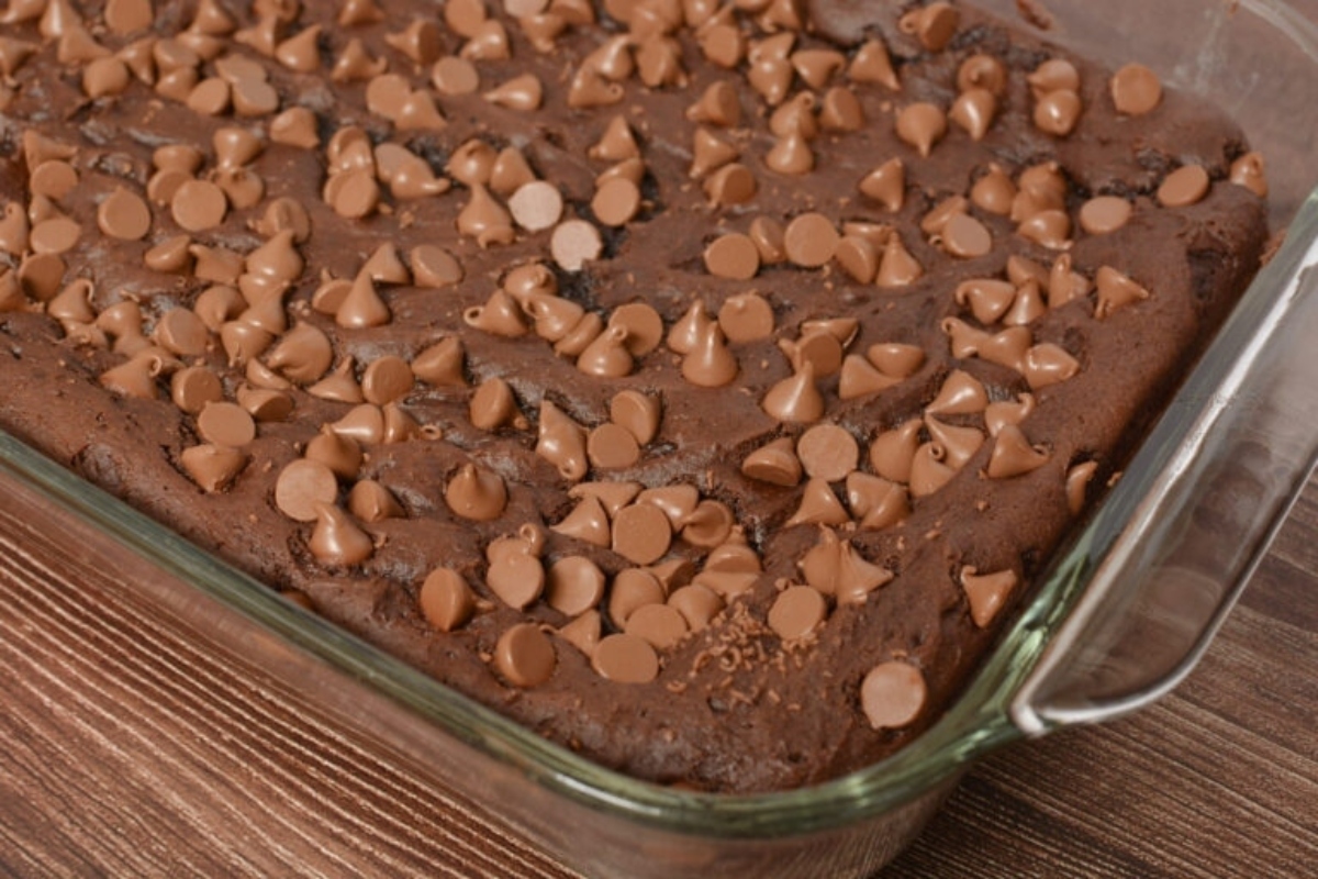 A chocolate cake with chocolate chips in a glass dish.