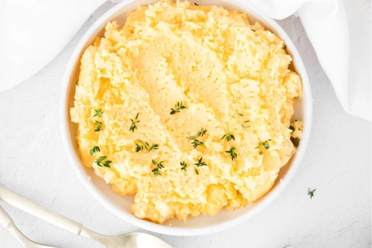 Mashed potatoes in a white bowl with a spoon.