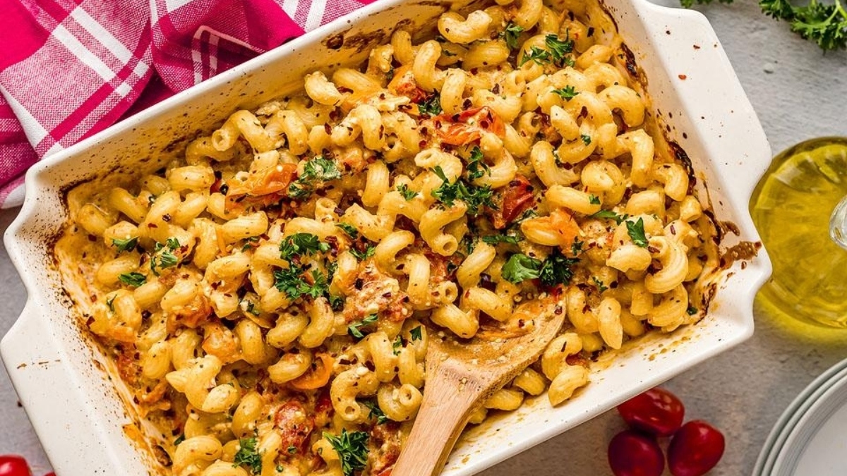 Feta pasta in a dish with tomatoes and herbs.