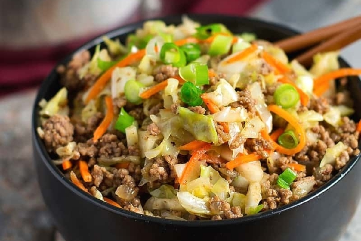 A bowl of meat and cabbage in a bowl with chopsticks.