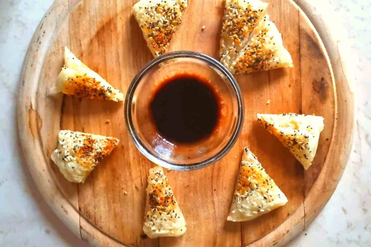 Fried wonton with dipping sauce on a wooden board.