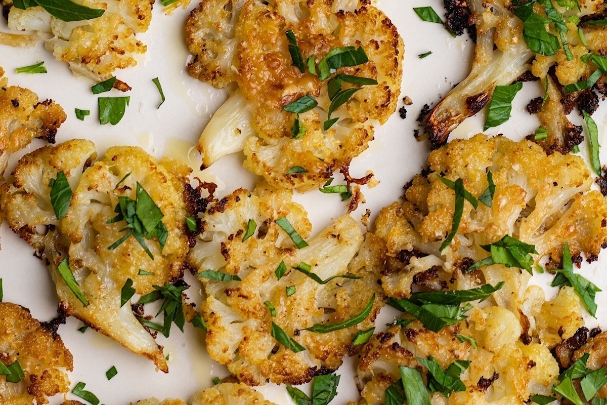 Roasted cauliflower on a white plate with herbs.