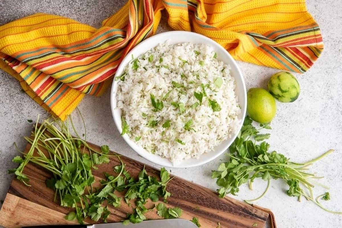 Mexican rice on a cutting board with limes and cilantro.