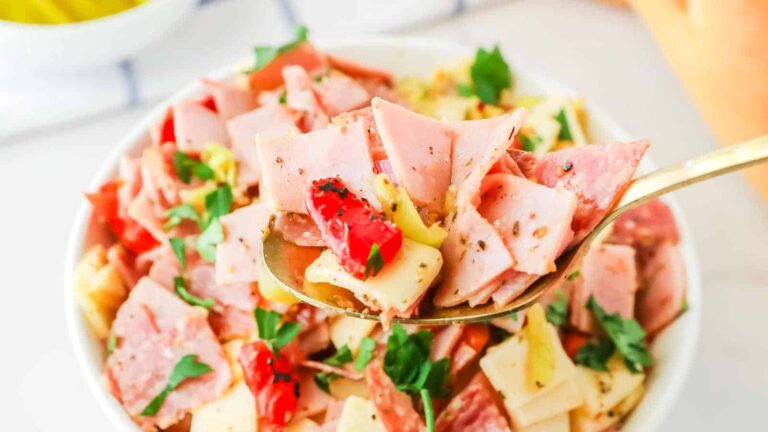 Ham and artichoke salad in a white bowl.