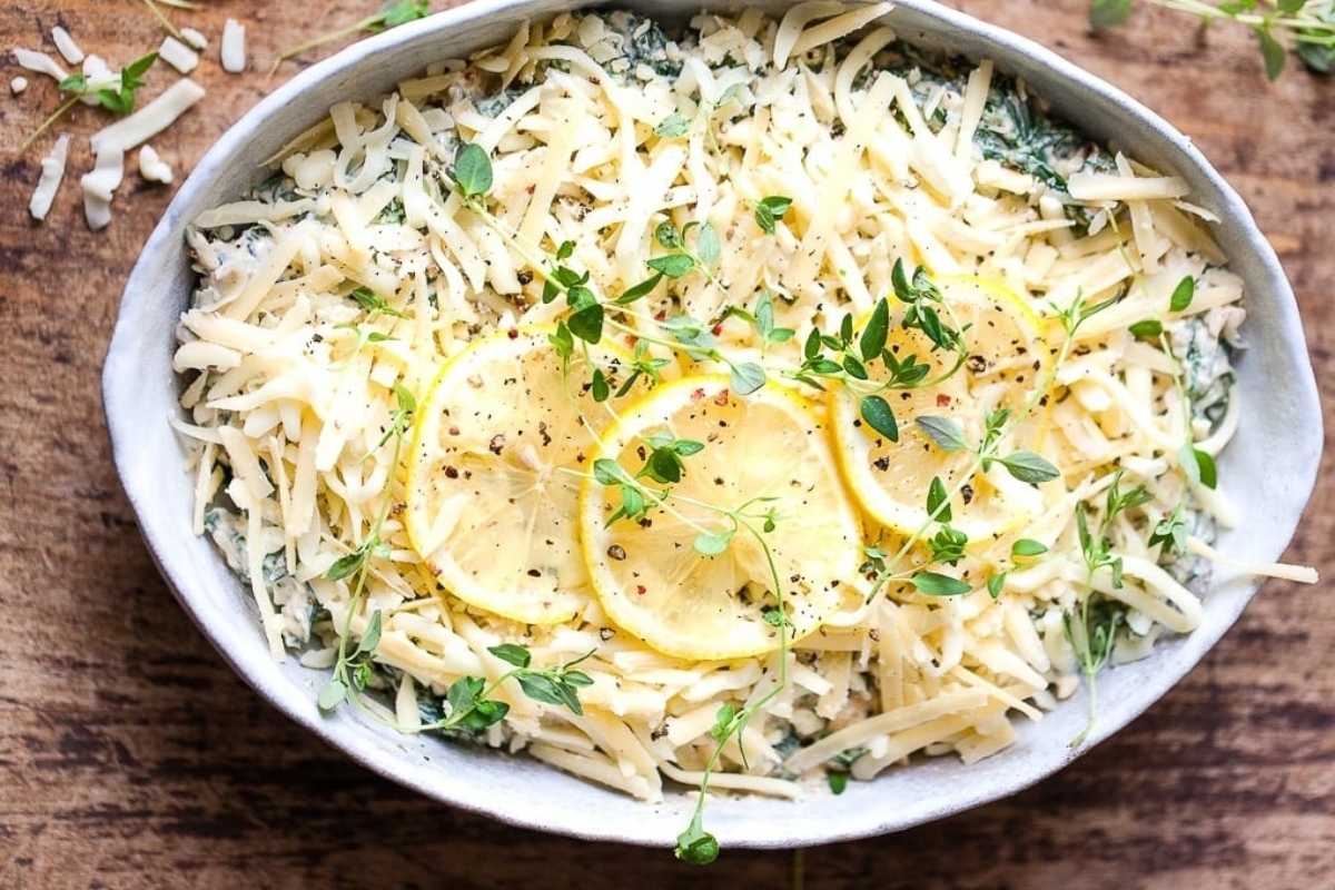 A bowl of ricotta and spinach dip with lemons.