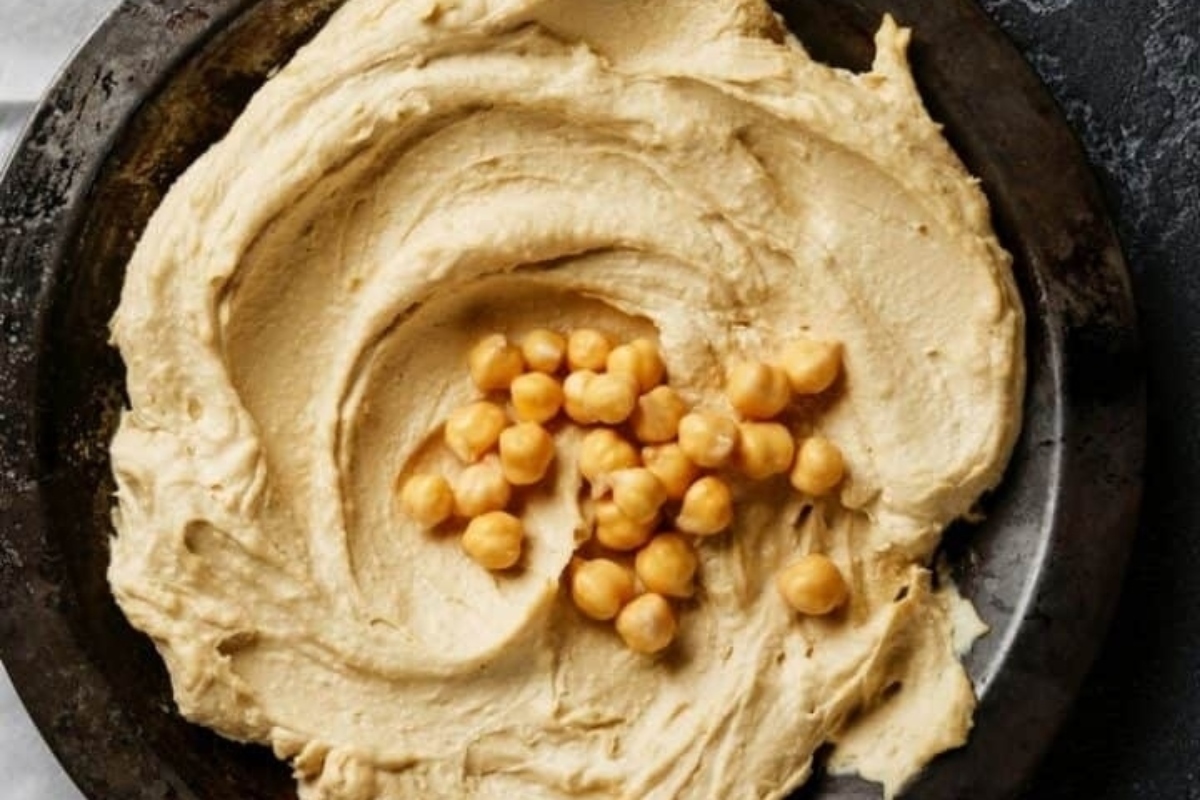 A bowl of hummus with chickpeas in it.
