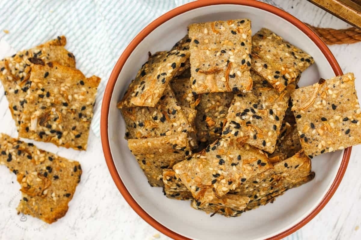 A bowl of crackers with sesame seeds in it.