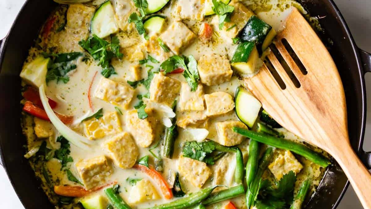 Skillet of green curry with wooden spoon.
