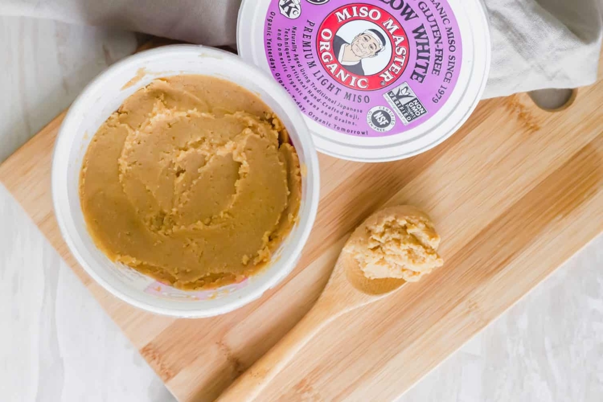 Peanut butter in a bowl next to a wooden spoon.