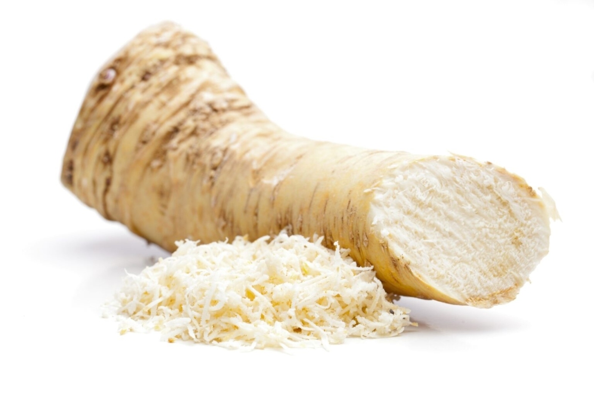 A piece of root and a pile of shredded rhubarb on a white background.