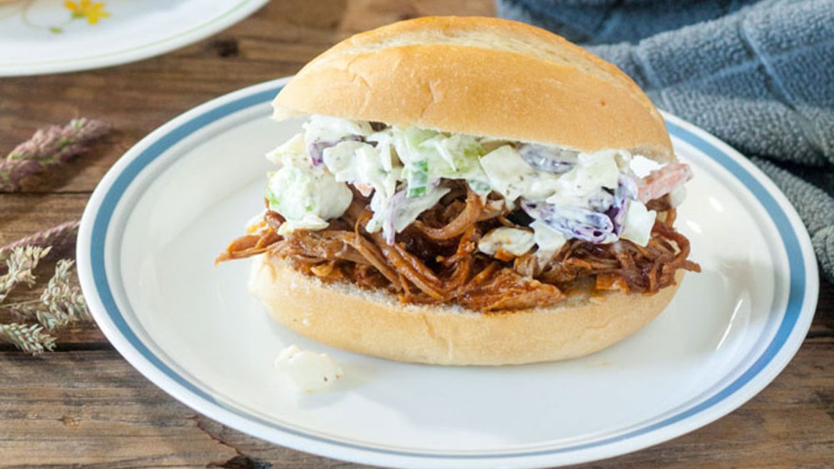 A pulled pork sandwich on a white plate.