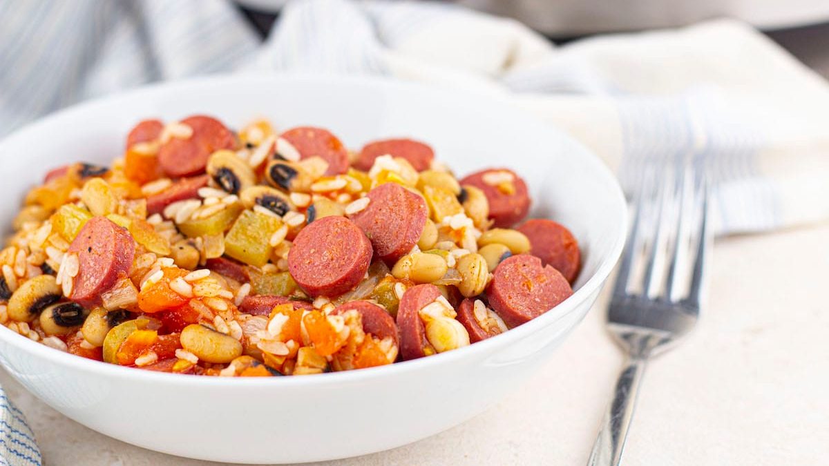 Hoppin John with smoked sausage in a white bowl.