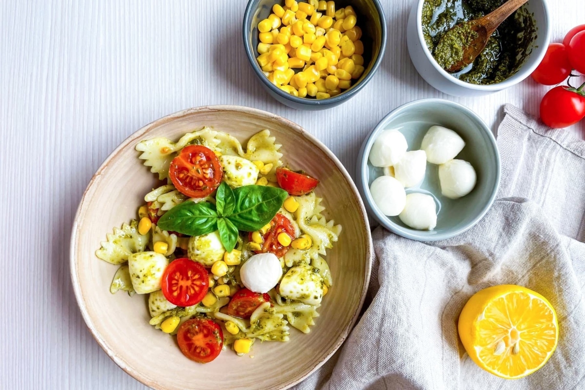 A bowl of pasta with tomatoes, mozzarella and basil.