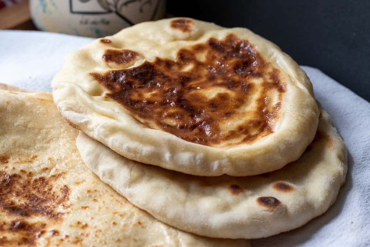 A stack of pita breads on a white napkin.