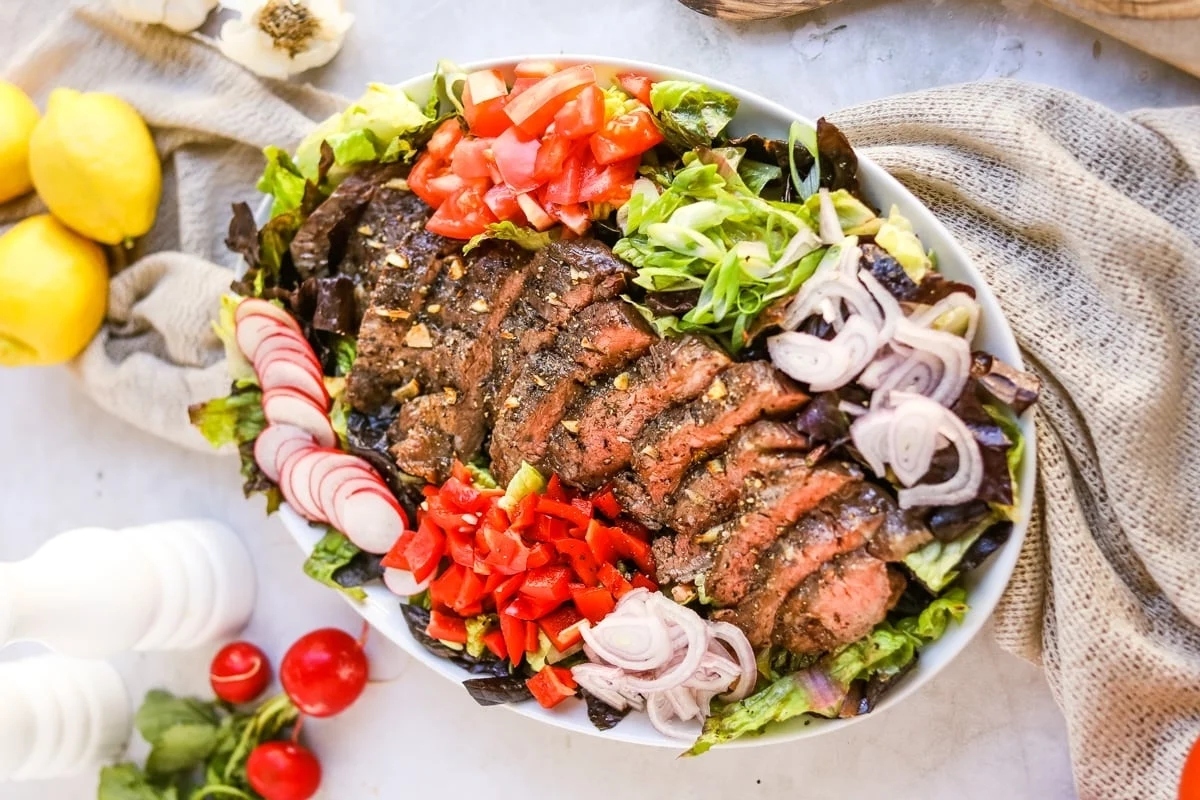 A salad with steak, tomatoes and onions.