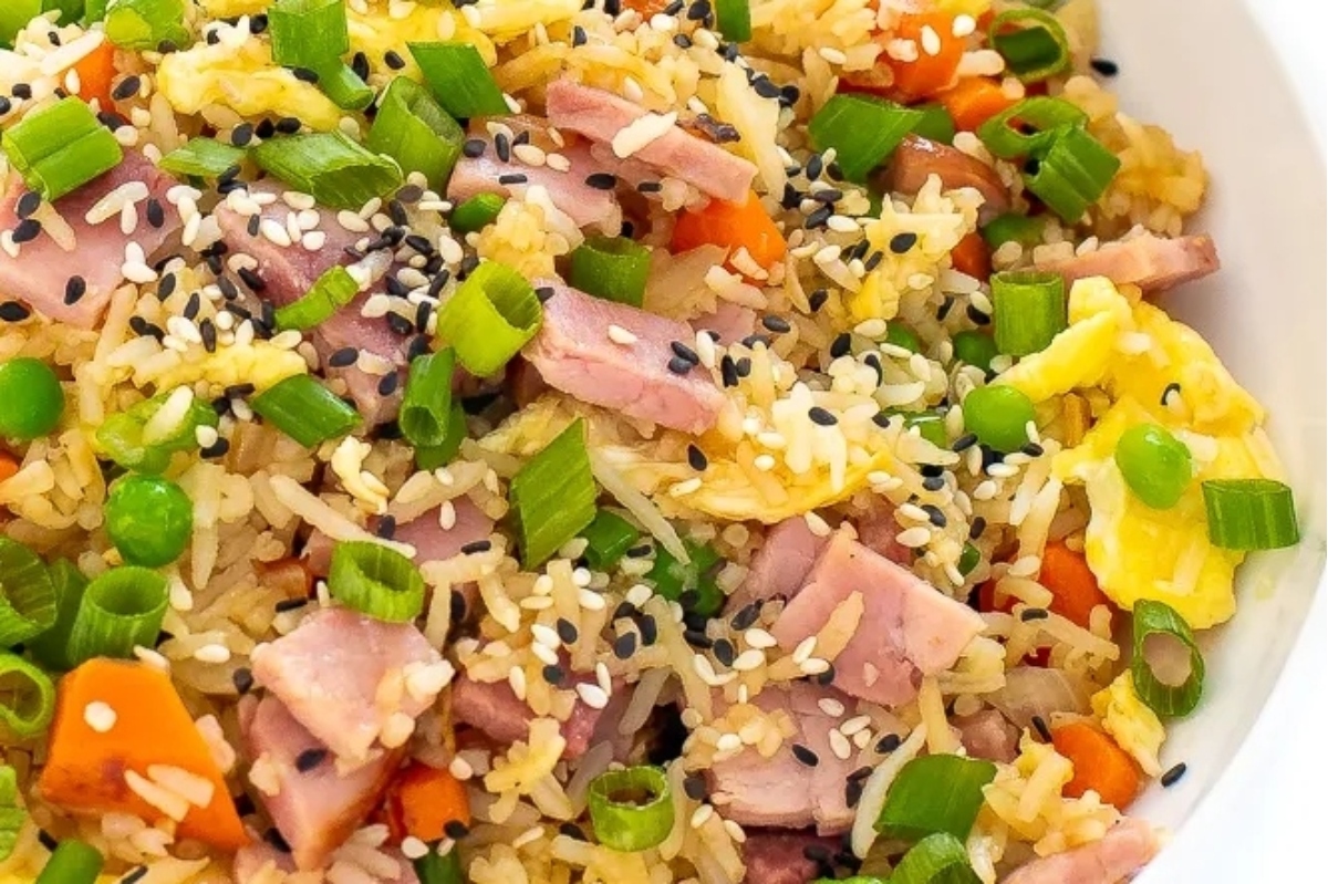 A bowl of fried rice with ham and vegetables.