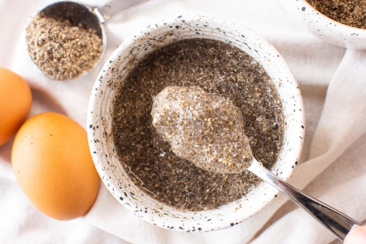 A spoonful of chia seeds in a bowl next to eggs.