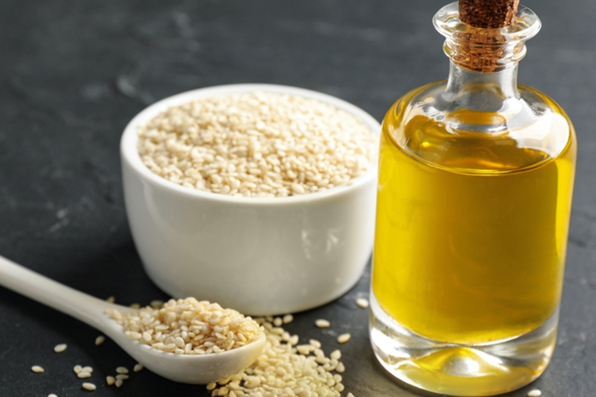 A bottle of sesame oil and sesame seeds.