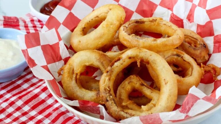 Onion rings in a bowl with dipping sauce.
