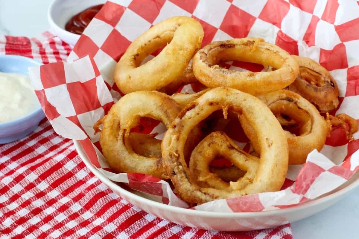 Onion rings in a bowl with dipping sauce.