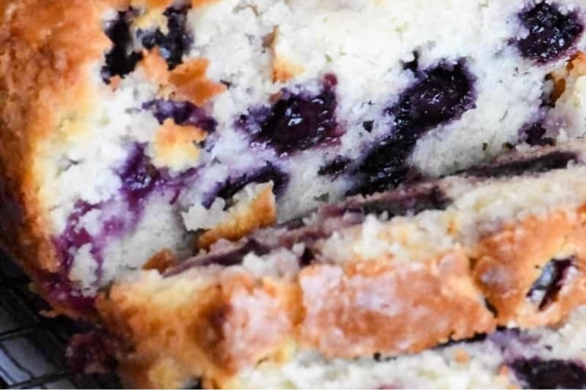A slice of blueberry bread on a cooling rack.