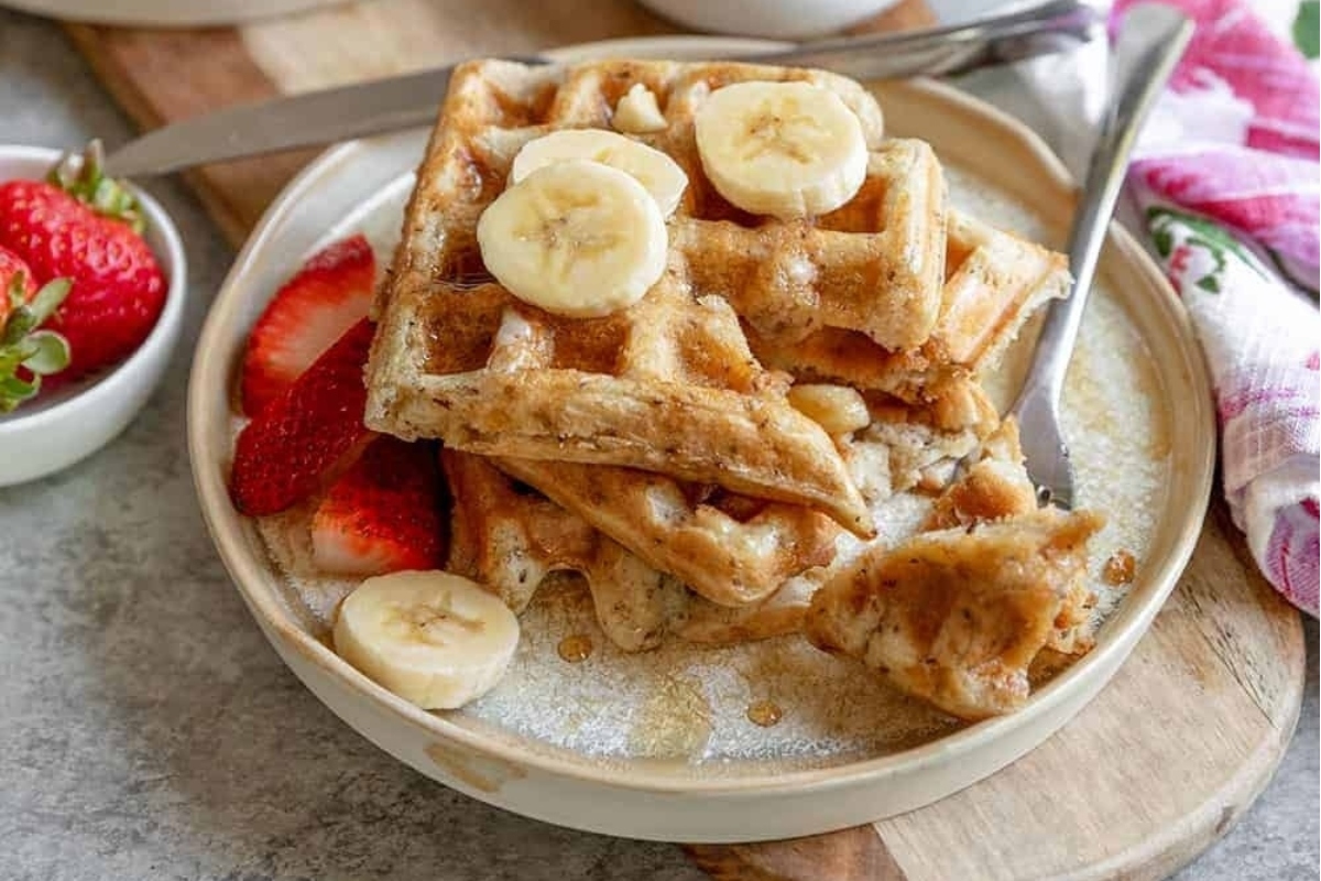 A plate of waffles with bananas and strawberries.