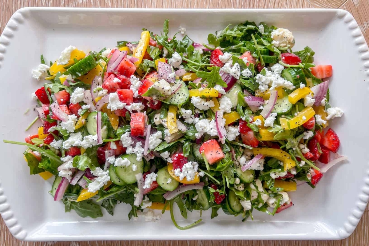 A salad with tomatoes, cucumbers and feta on a white plate.
