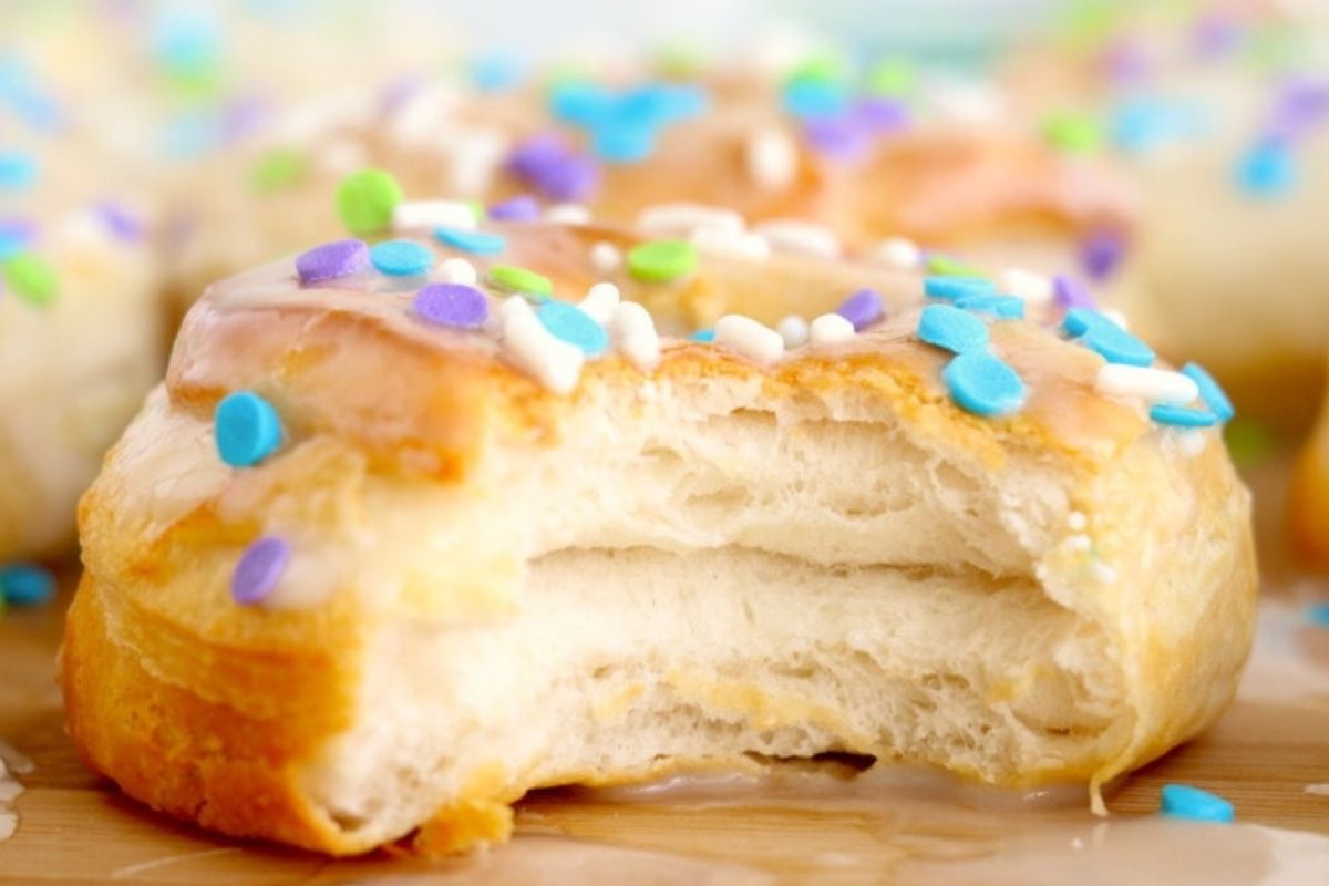 A close-up of a partially eaten pastry topped with colorful sprinkles, showing its flaky layers crafted from refrigerated dough.