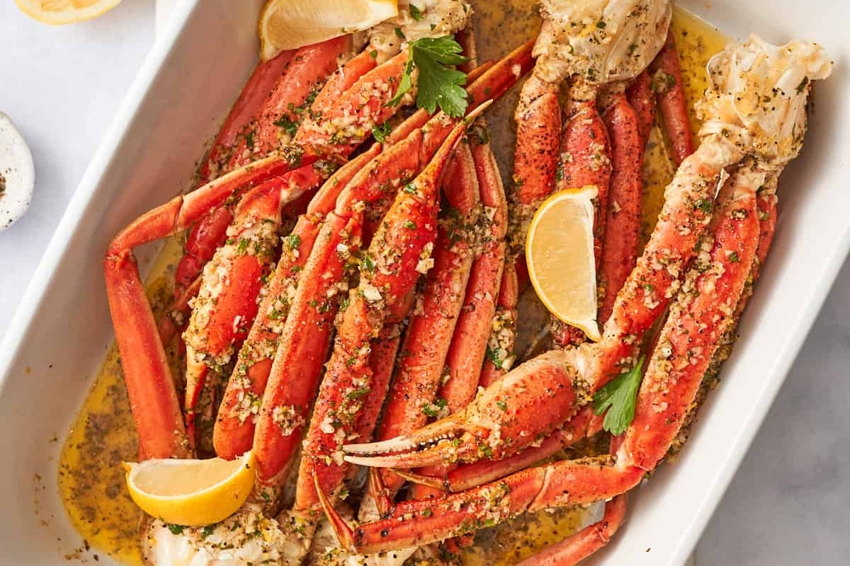 Cooked crab legs garnished with parsley and lemon slices in a dish.