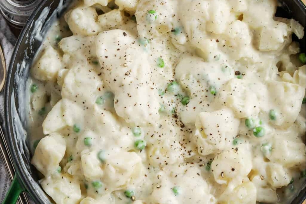 Mashed potatoes with peas in a skillet.