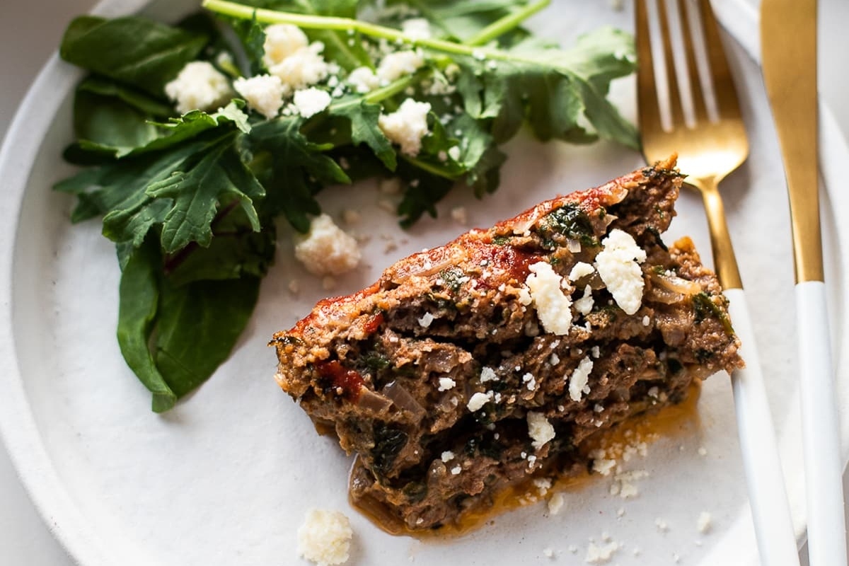 A plate of meatloaf with a salad on it.