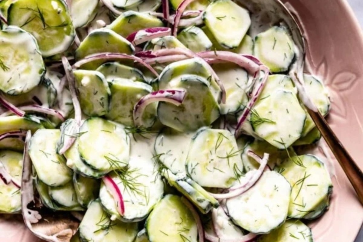 Cucumber salad in a pink bowl with a fork.