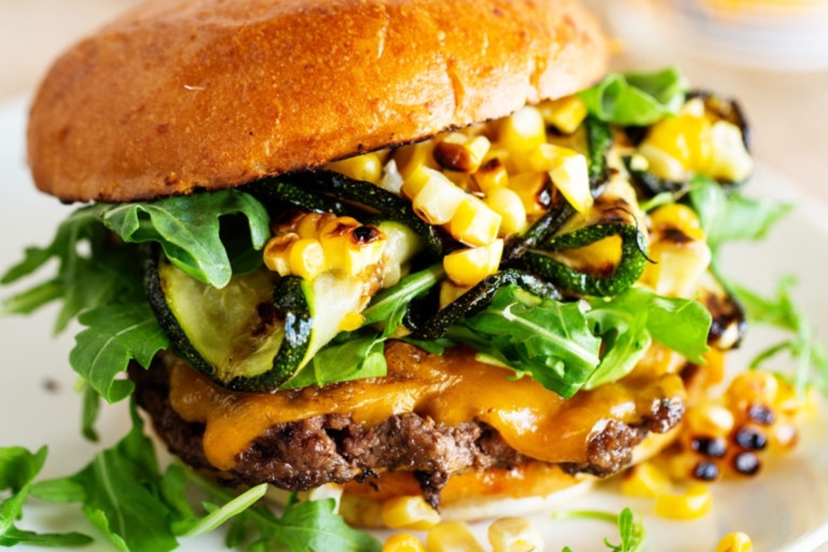 A burger with grilled corn and arugula.