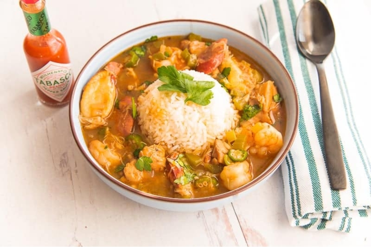 A bowl of gumbo with rice and sausage.
