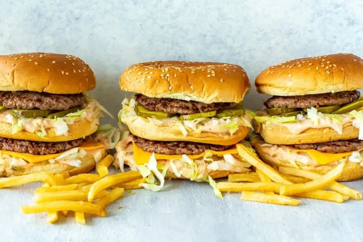 Four burgers and french fries are stacked on top of each other.