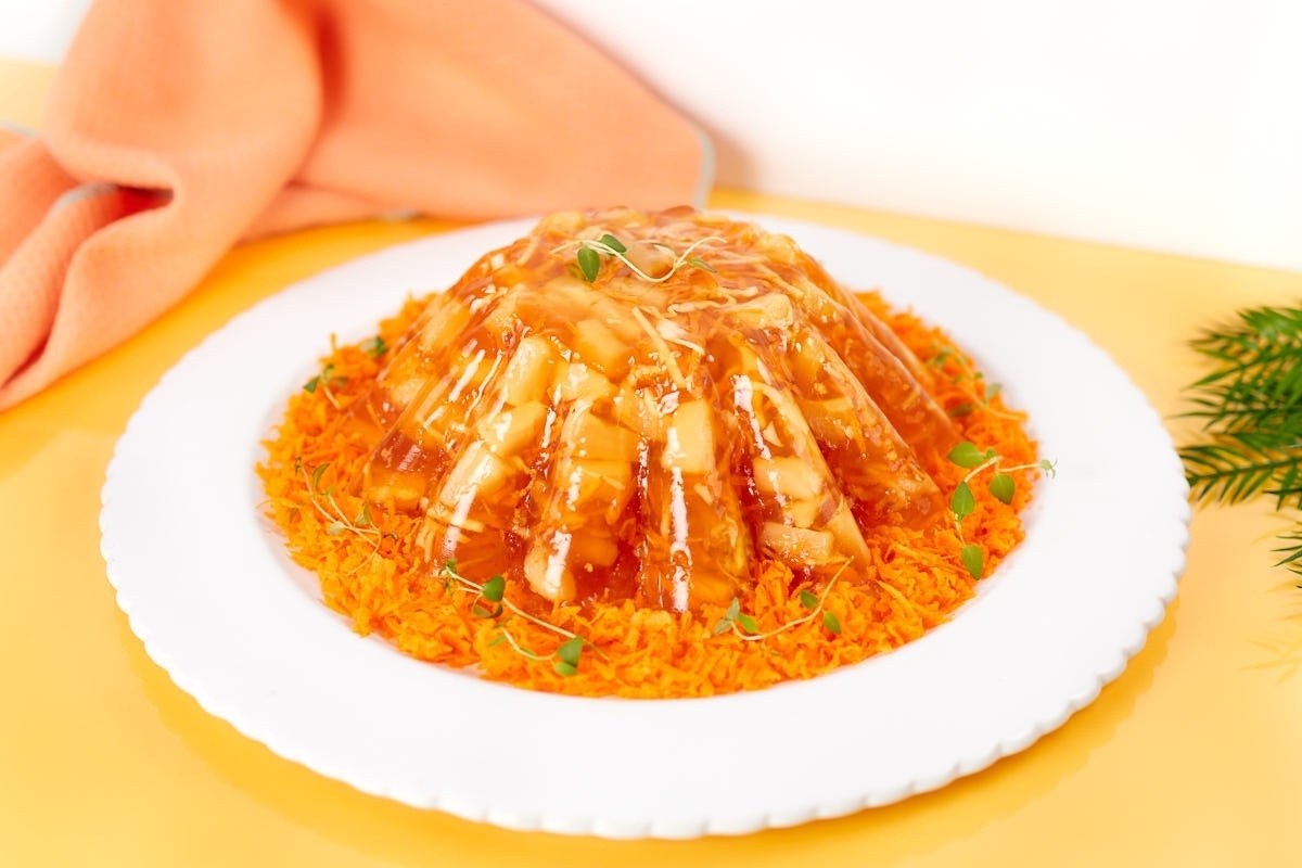 A molded gelatin salad on a bed of shredded carrots, served on a white plate.