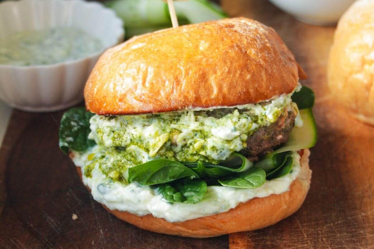 Pesto burgers on a wooden cutting board.