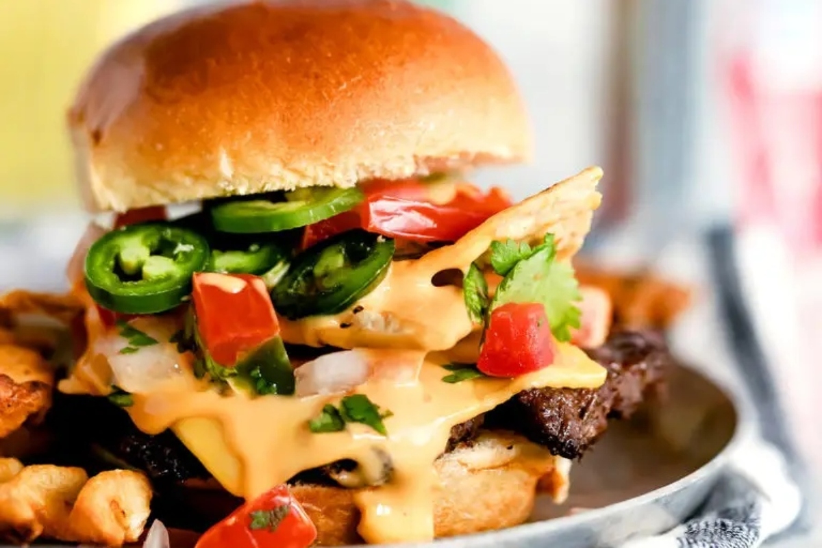 A burger with cheese and peppers on a plate.