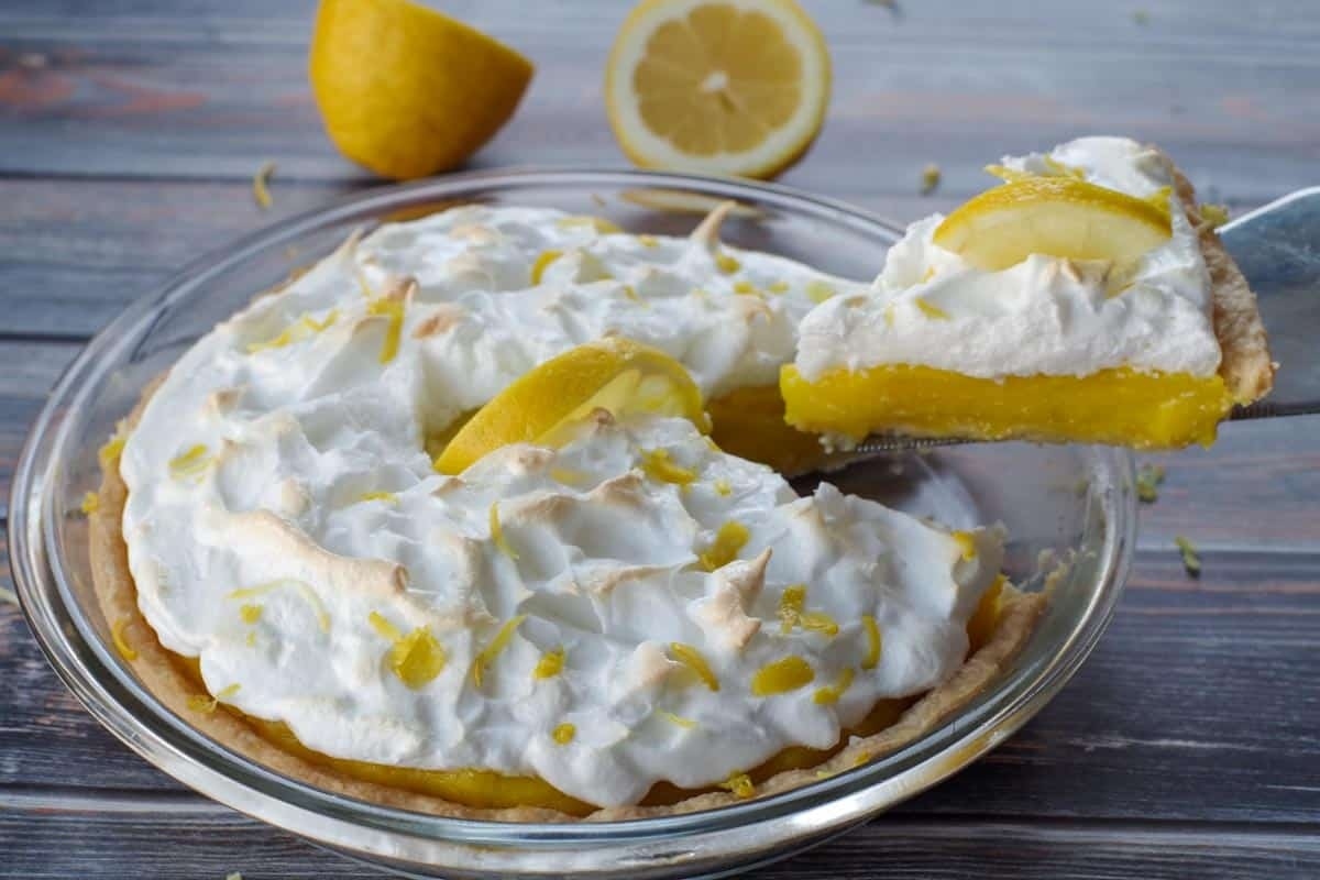 A slice of lemon pie with whipped cream and lemon slices.